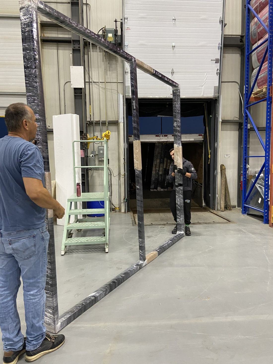 Two workers carrying a large frame in the factory