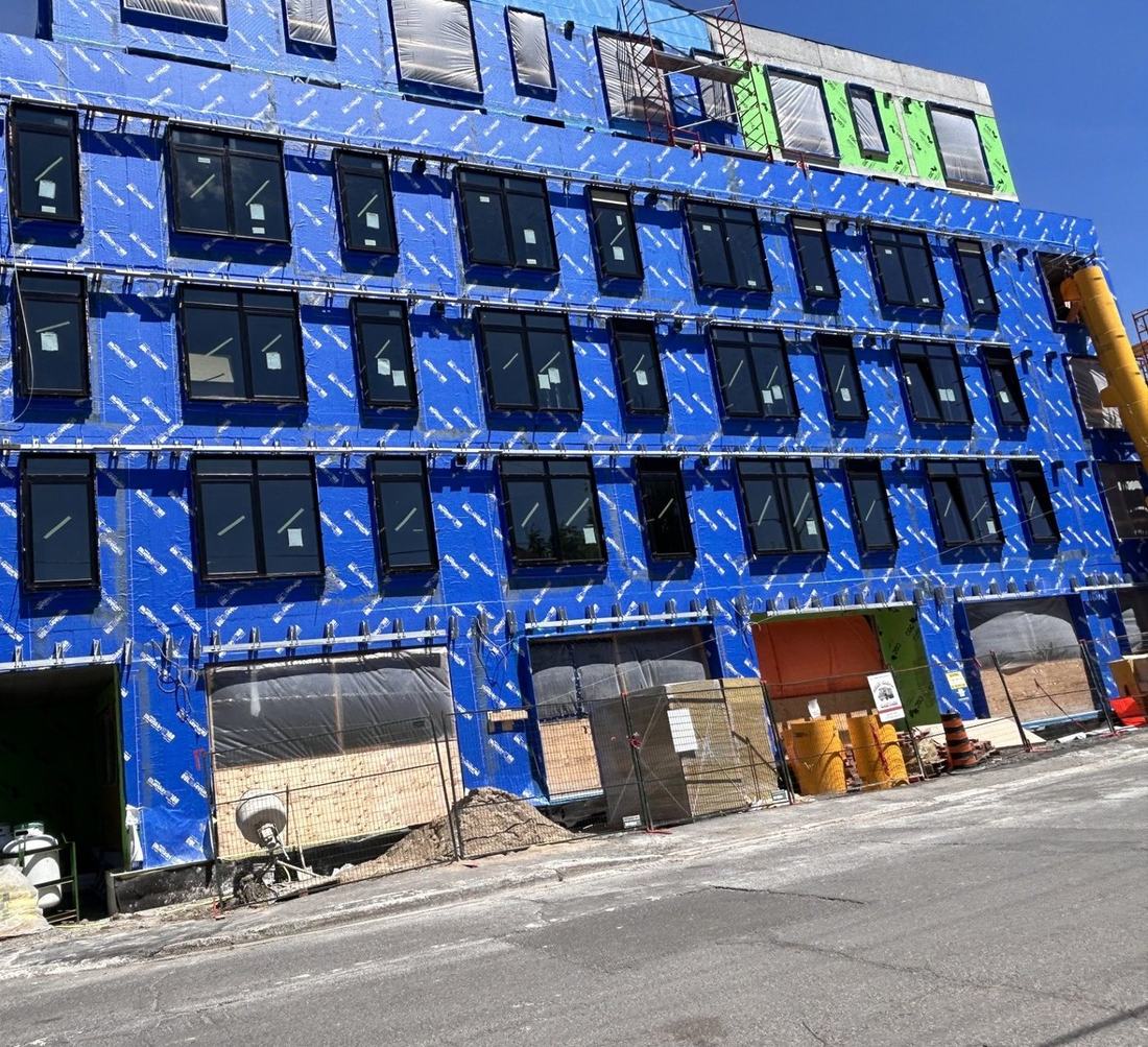 Multi-unit building under construction with new black-framed windows